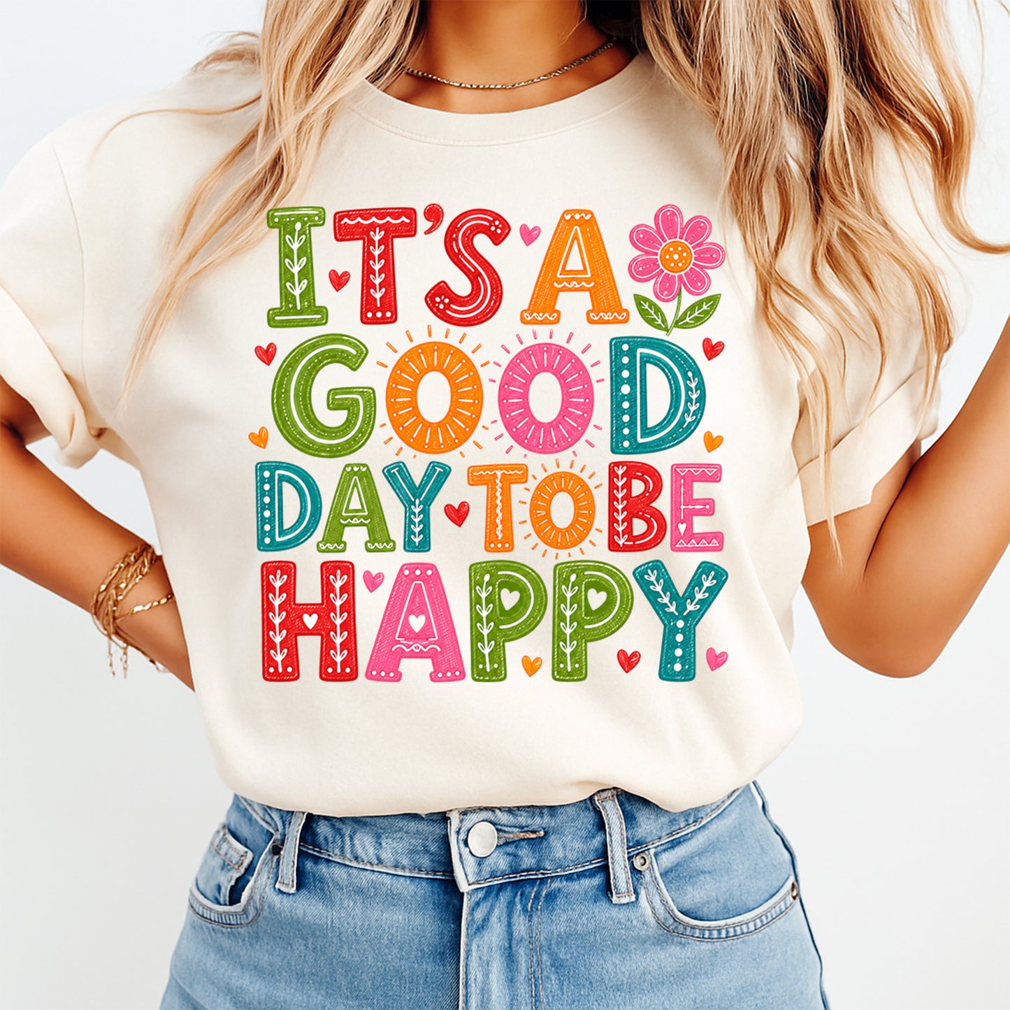 Person wearing a white t-shirt with colorful text 'It's a good day to be happy' and denim shorts on a light background.