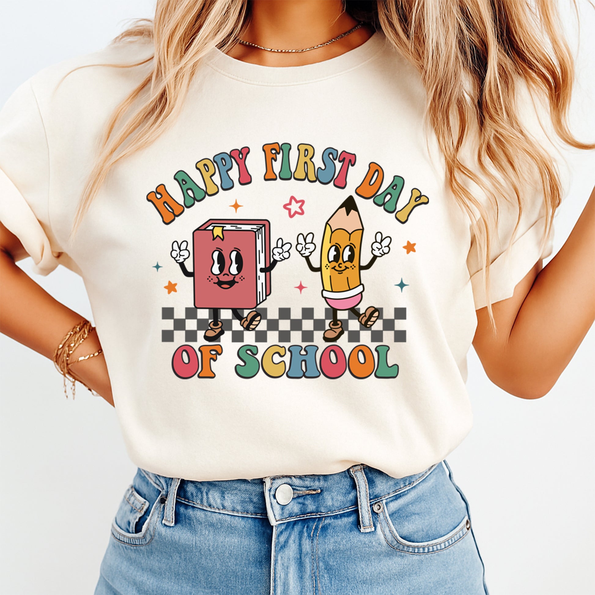 Person wearing a t-shirt with 'Happy First Day of School' design featuring a book and pencil.
