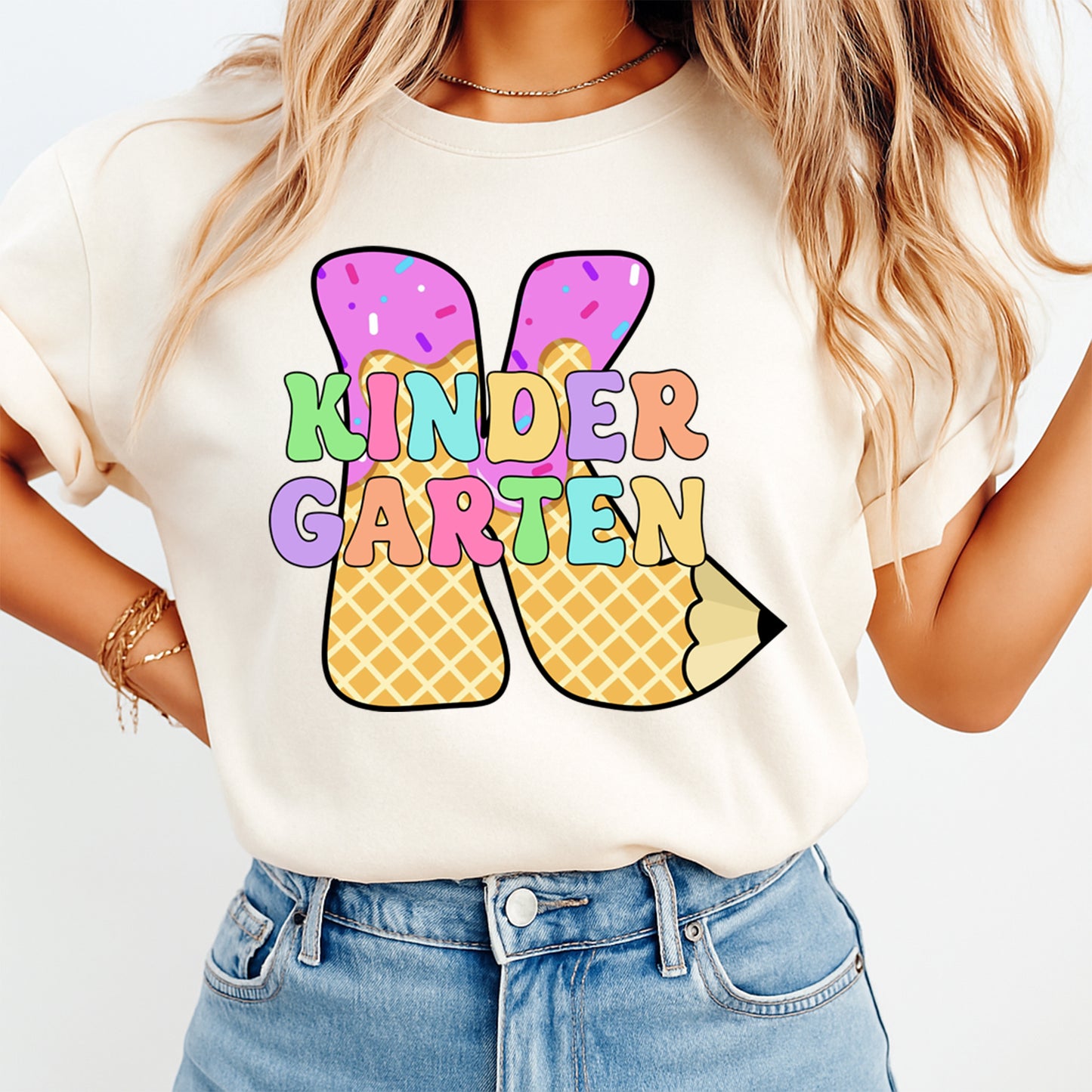 Person wearing a white t-shirt with colorful 'KINDERGARTEN' design and denim shorts on a light background
