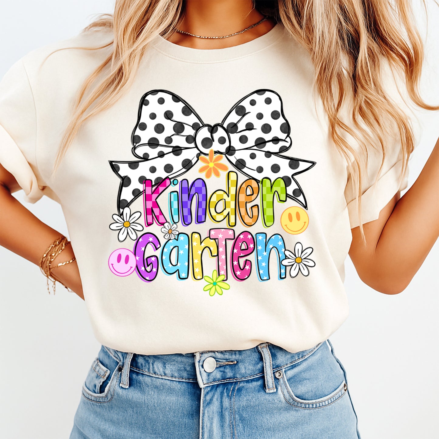 Person wearing a white t-shirt with a colorful 'Kindergarten' design and a polka dot bow.
