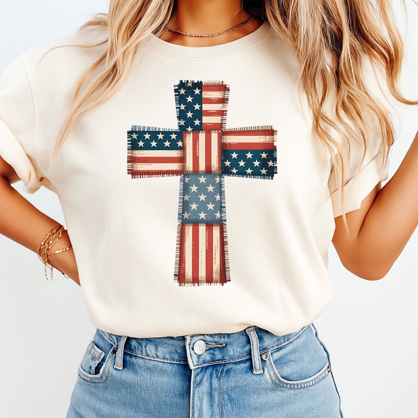 Person wearing a white t-shirt with an American flag cross design on a plain background