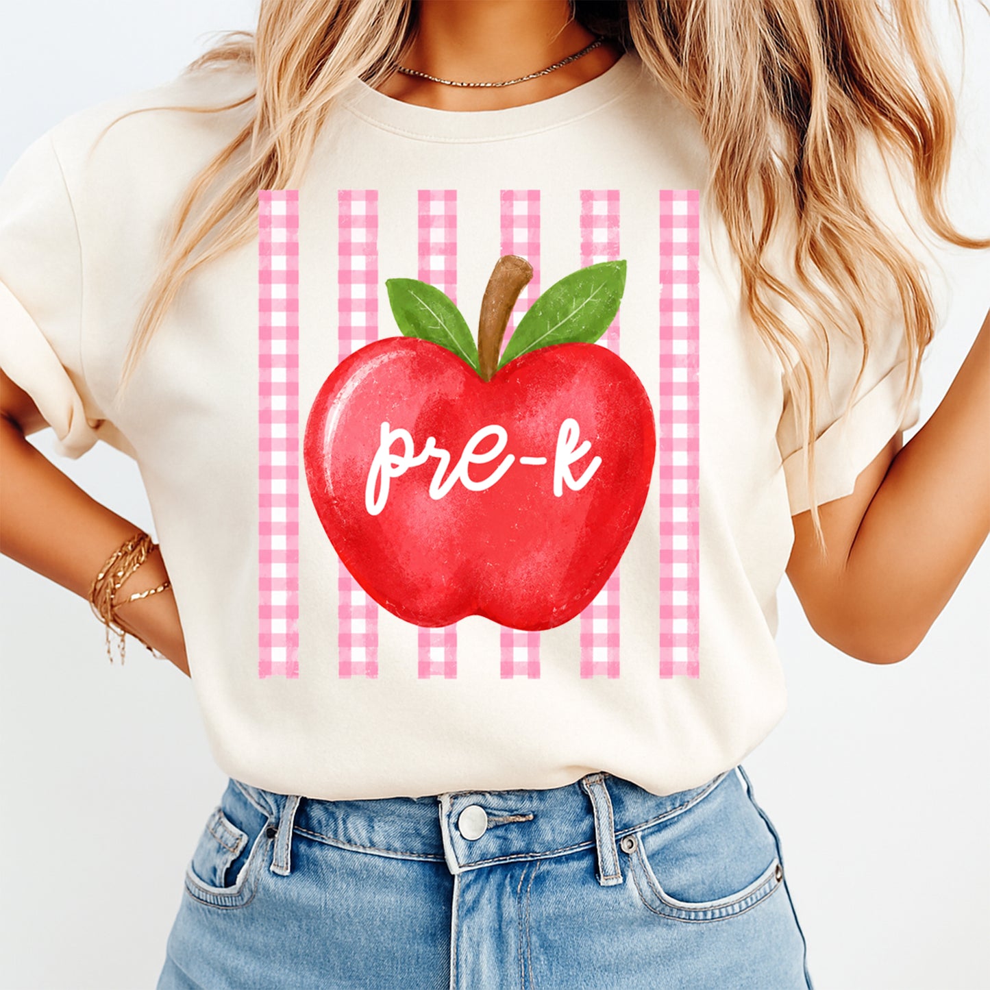 Person wearing a t-shirt with a red apple graphic and 'pre-k' text on a checkered background.