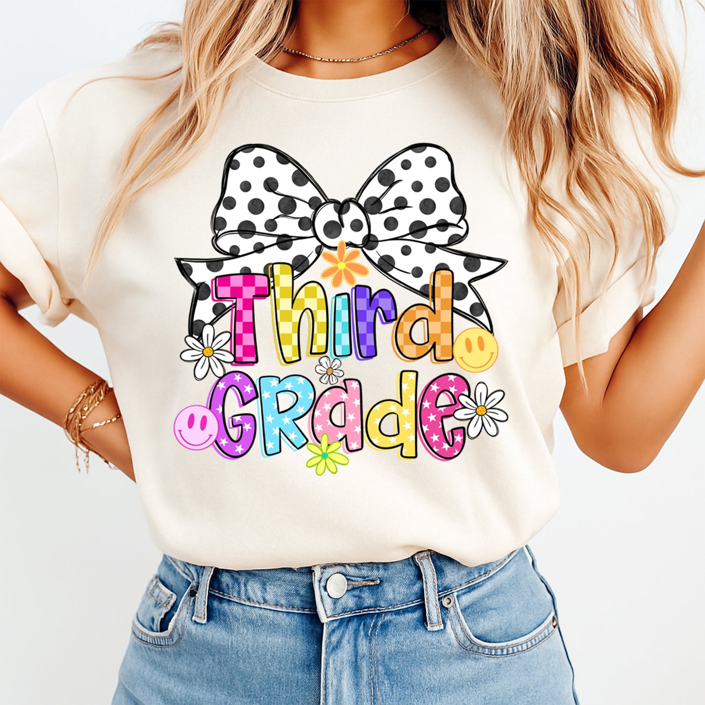 Person wearing a white t-shirt with 'Third Grade' and a bow design.