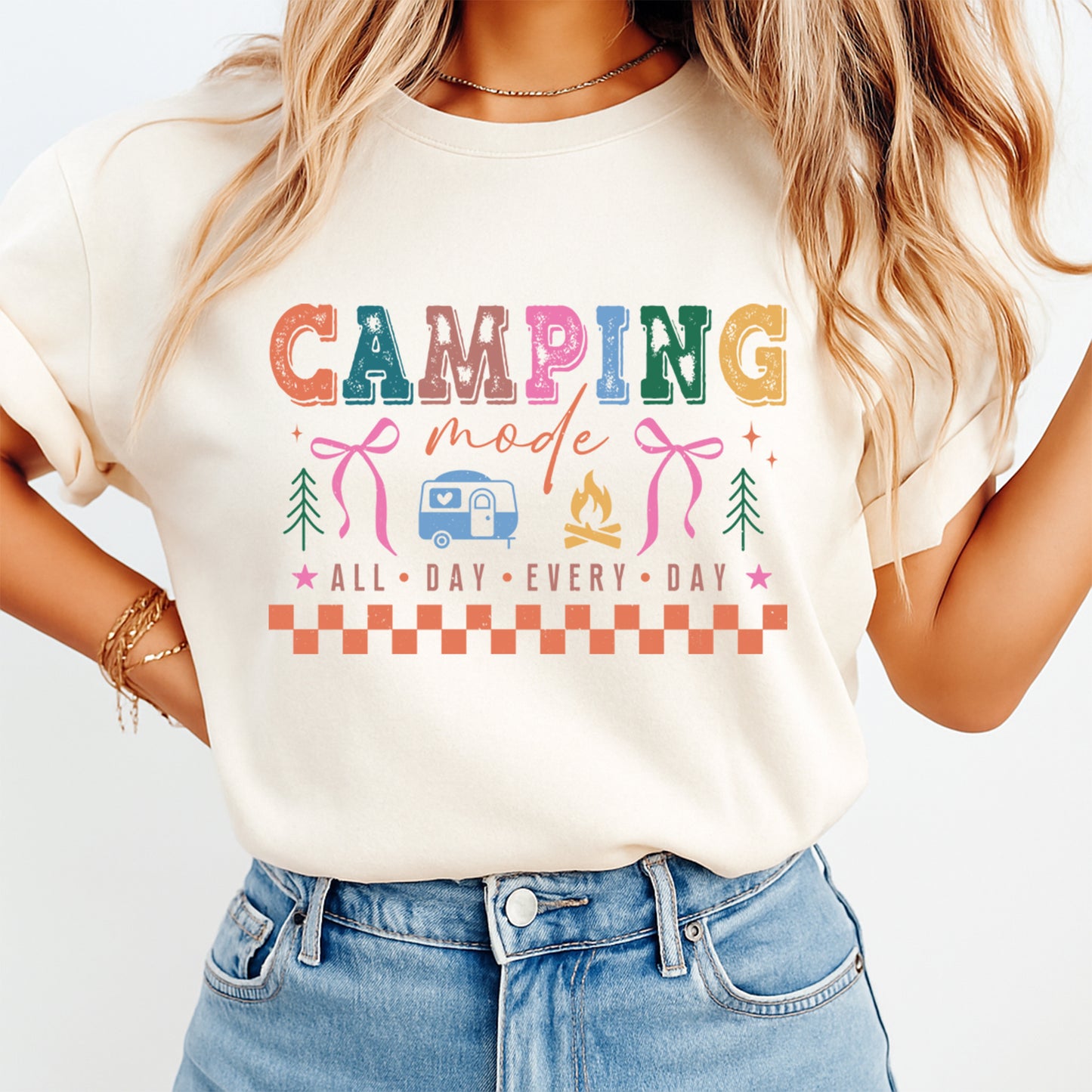 Person wearing a white t-shirt with colorful 'Camping Mode' design on a plain background