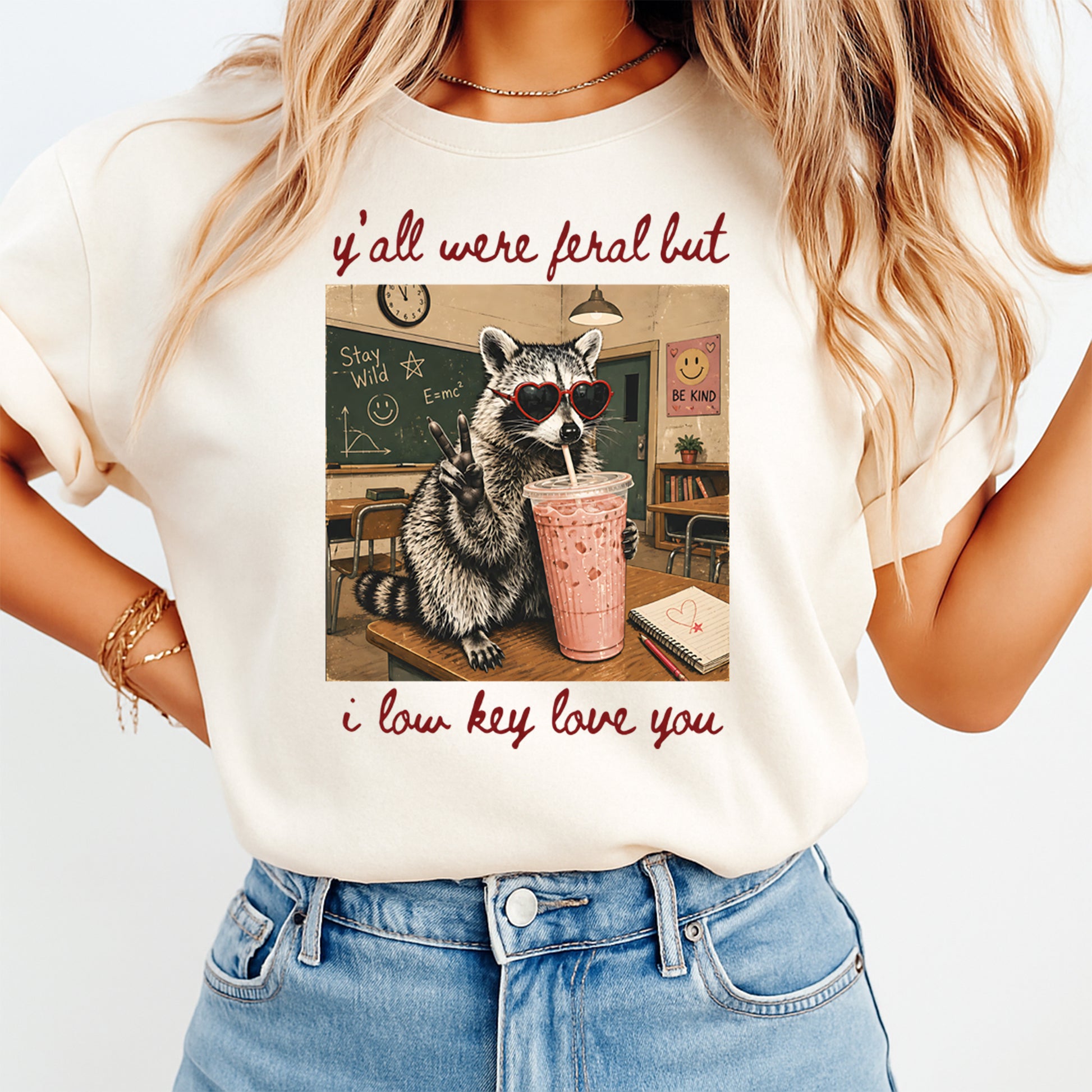 Person wearing a t-shirt with a raccoon graphic and text in a classroom setting.