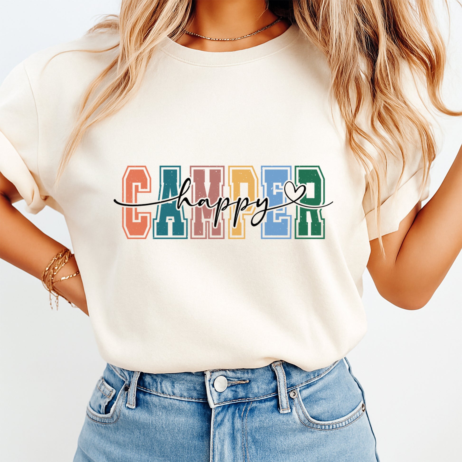 Person wearing a white t-shirt with 'Happy Camper' text in colorful letters on a plain background