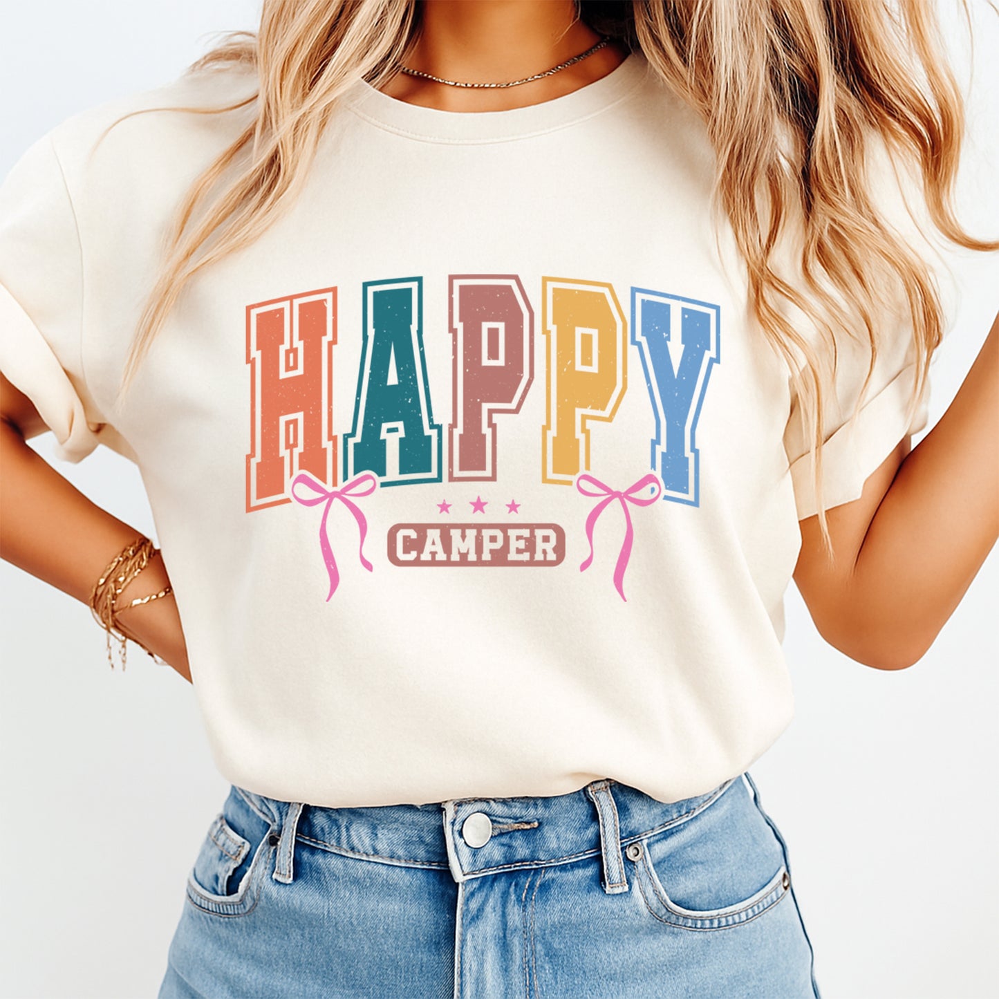Person wearing a white t-shirt with 'Happy Camper' text and colorful design.