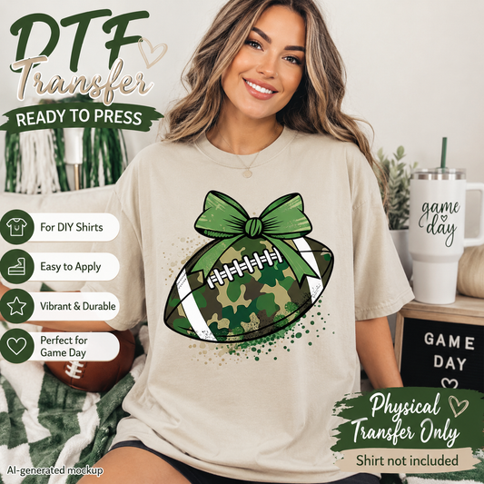 A woman wearing a beige graphic t-shirt featuring a football design with a green camouflage pattern and a large green bow. The image is a promotional mockup for a physical transfer, with text overlays detailing product features like 'DTF Transfer Ready to Press' and 'Physical Transfer Only'.