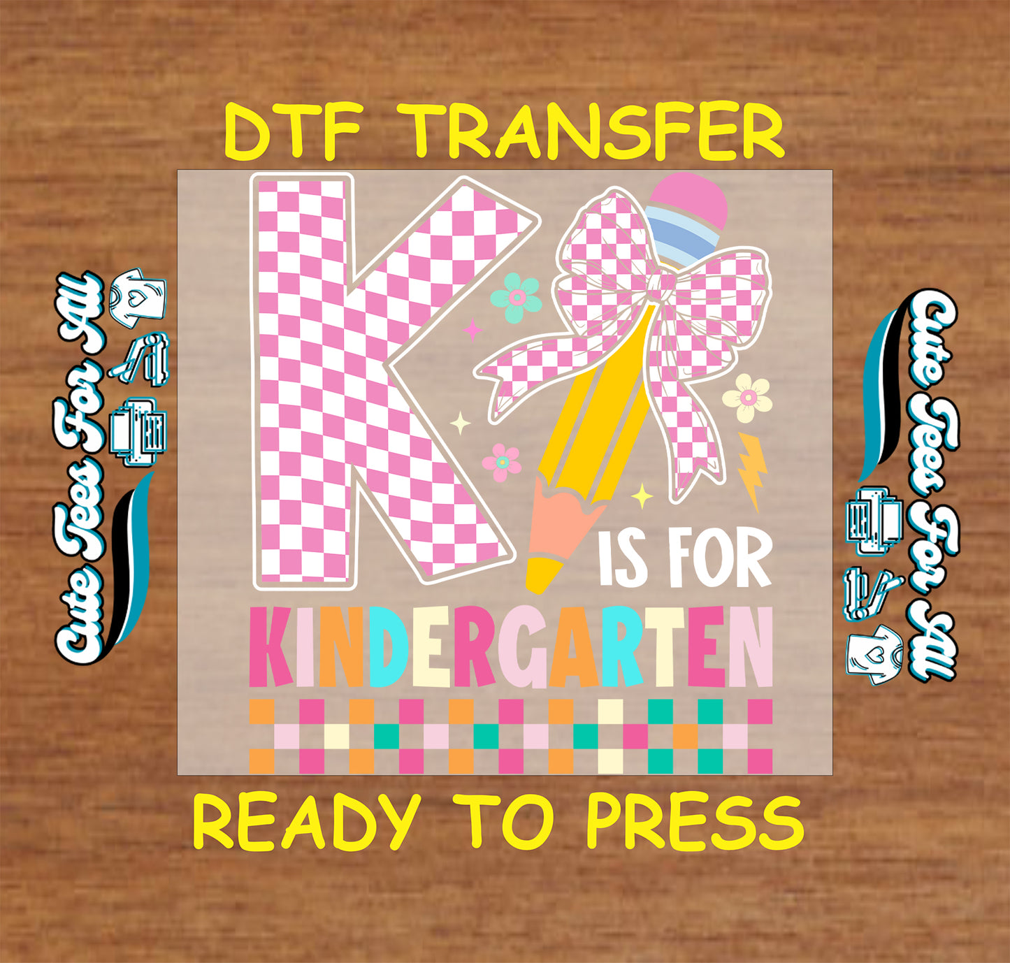A DTF transfer design preview featuring a large pink and white checkered letter K, a pink checkered bow, a yellow pencil, and the words 'IS FOR KINDERGARTEN' on a tan rectangular transfer sheet, set against a brown wood background with yellow text reading 'DTF TRANSFER' and 'READY TO PRESS'.