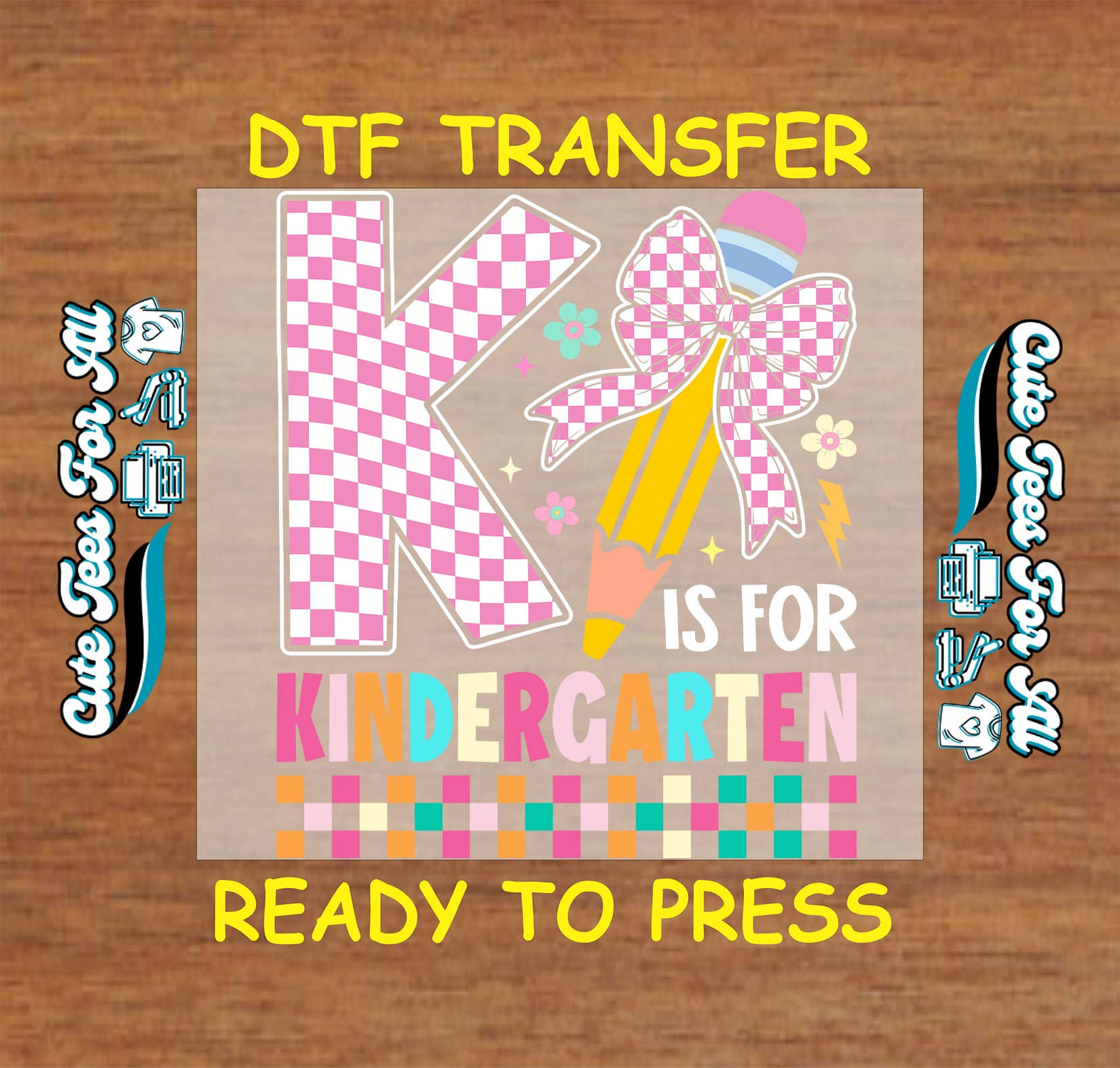 A DTF transfer design preview featuring a large pink and white checkered letter K, a pink checkered bow, a yellow pencil, and the words 'IS FOR KINDERGARTEN' on a tan rectangular transfer sheet, set against a brown wood background with yellow text reading 'DTF TRANSFER' and 'READY TO PRESS'.