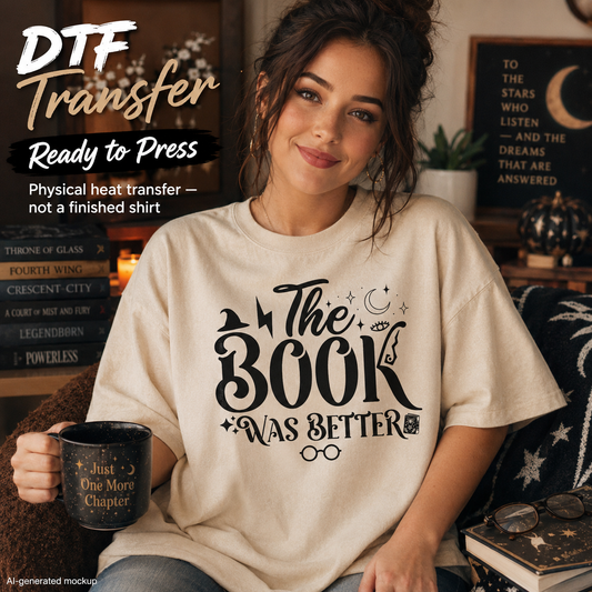 A woman seated indoors wearing a cream T-shirt with large black decorative text reading 'The Book Was Better.' She holds a black mug, and the scene includes promotional text in the upper left and room decor in the background.