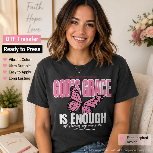 A smiling woman wearing a black graphic T-shirt with a pink and white butterfly design and the text 'GOD'S GRACE IS ENOUGH Always by my side'. The photo is styled in a cozy indoor setting with a framed 'Faith Hope Love' print on the wall, a candle, and flowers.
