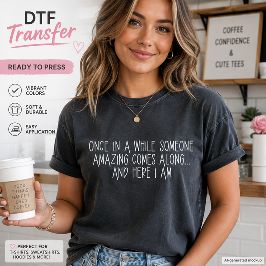 A woman wearing a dark charcoal gray T-shirt with white printed text that reads 'ONCE IN A WHILE SOMEONE AMAZING COMES ALONG.