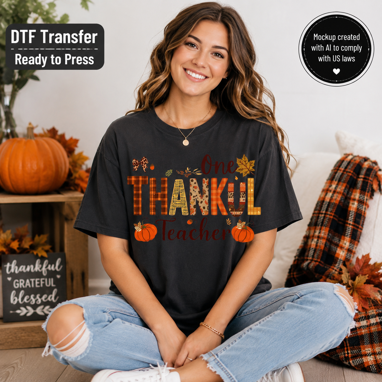 A woman sits cross-legged wearing a black graphic T-shirt with autumn-themed lettering that reads 'One Thankful Teacher' in orange, yellow, and brown tones. The scene includes pumpkins, fall leaves, a plaid throw blanket, and promotional text badges reading 'DTF Transfer Ready to Press' and 'Mockup created with AI to comply with US laws.