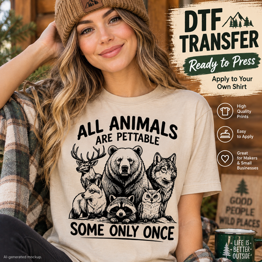 A woman wearing a beige graphic T-shirt with black printed text reading 'ALL ANIMALS ARE PETTABLE SOME ONLY ONCE' and an illustration of bears, wolves, a deer, a raccoon, and an owl. The scene is outdoors with a beanie, plaid shirt, and a promotional graphic panel about DTF transfer on the right.