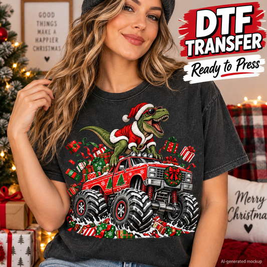 A woman wearing a dark gray graphic t-shirt featuring a green dinosaur riding a red monster truck decorated with Christmas ornaments and wrapped in holiday greenery. The background shows a cozy Christmas tree and holiday decorations, with a 'DTF TRANSFER Ready to Press' graphic overlay in the top right.