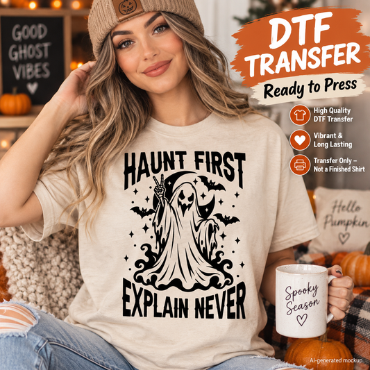 A woman wearing a beige graphic T-shirt with a black 'HAUNT FIRST EXPLAIN NEVER' ghost design, styled in a cozy fall setting with pumpkins and a mug. The image includes promotional text overlays for a DTF transfer product.
