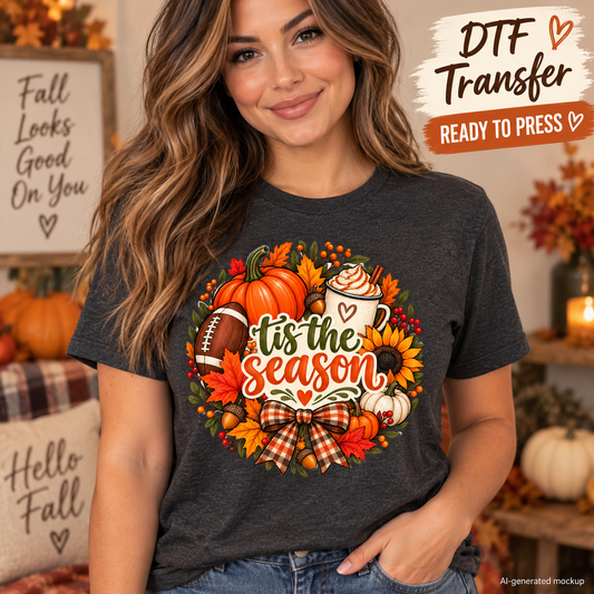 AI-generated mockup of a woman wearing a charcoal T-shirt with a Tis the Season fall design featuring pumpkins, a football, and a gingham bow.