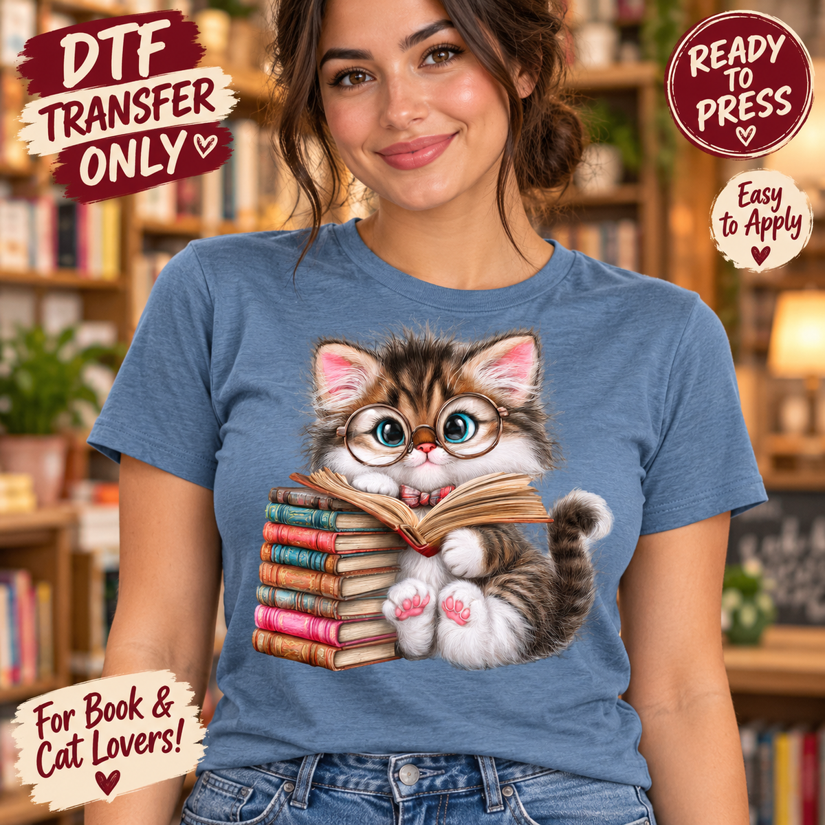 A woman wearing a blue graphic t-shirt with a cartoon illustration of a bookish kitten reading. The background is a blurred bookshelf.