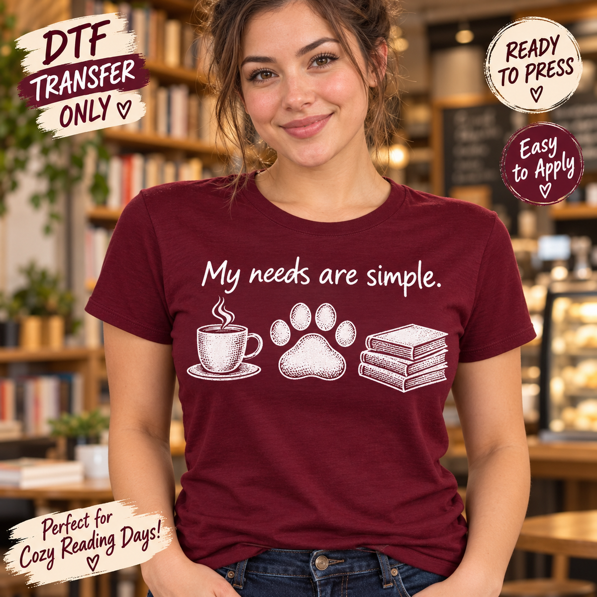 Woman in a maroon tee modeling white My Needs Are Simple DTF artwork with a steaming coffee cup, paw print, and stacked books.