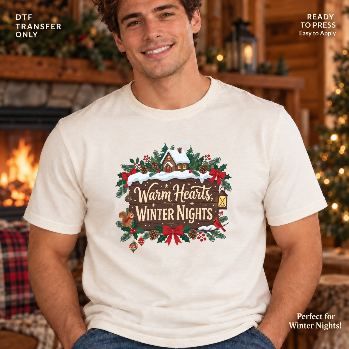 Lifestyle mockup of a man wearing a white shirt showing Warm Hearts Winter Nights lettering with a snowy cabin, evergreen branches, and red bows. DTF transfer only; shirt not included.