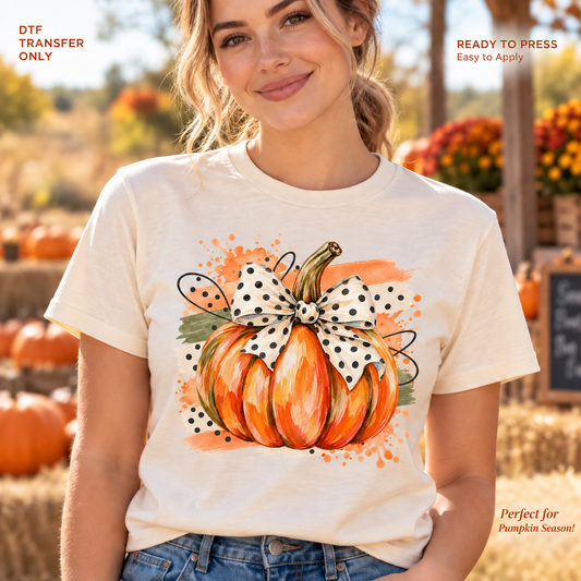 Lifestyle mockup of a woman wearing a cream shirt showing Orange watercolor pumpkin with a cream and black polka dot bow. DTF transfer only; shirt not included.
