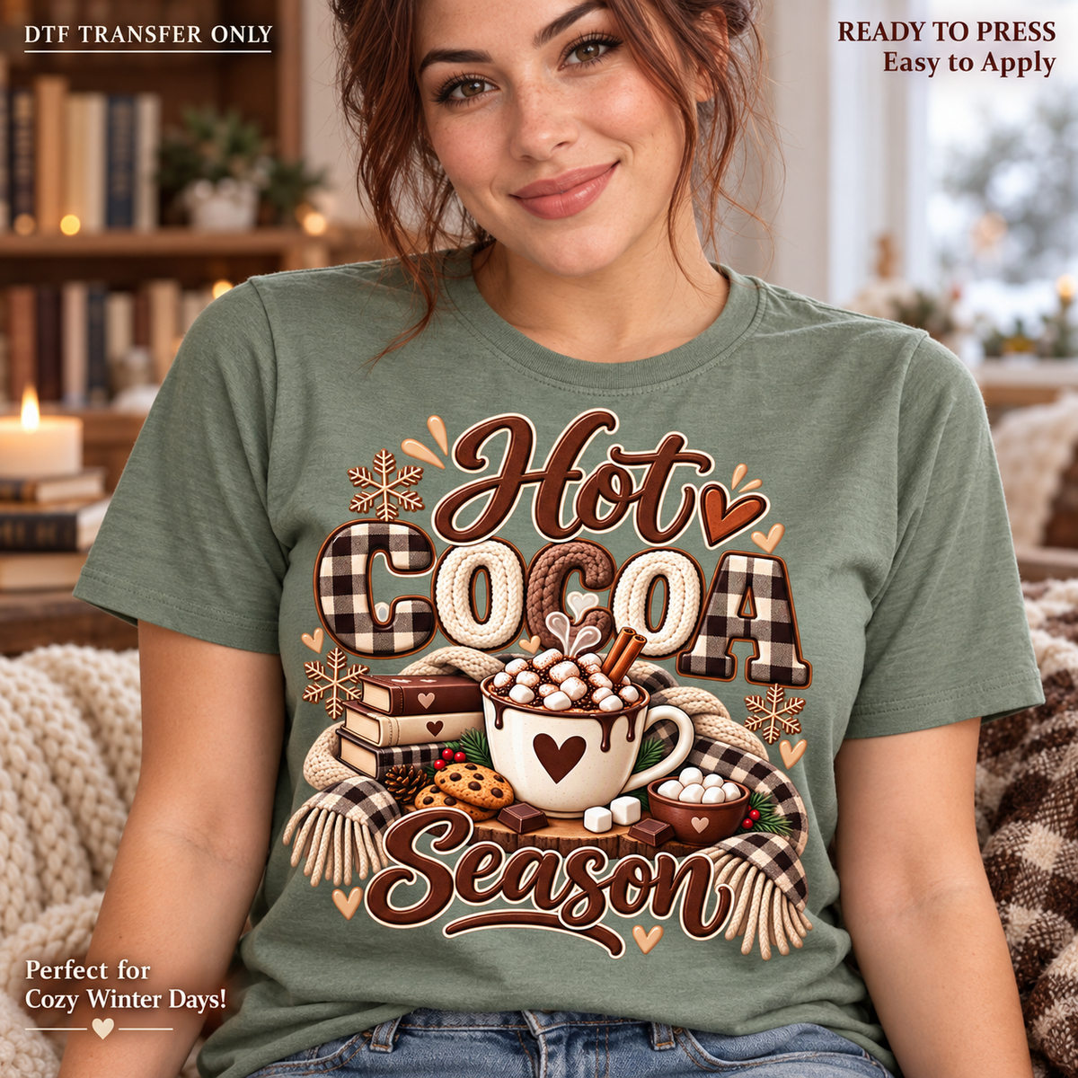 Lifestyle mockup of a woman wearing a sage green shirt showing Hot Cocoa Season message with cocoa mug, stacked books, cinnamon sticks, and large checked bow. DTF transfer only; shirt not included.