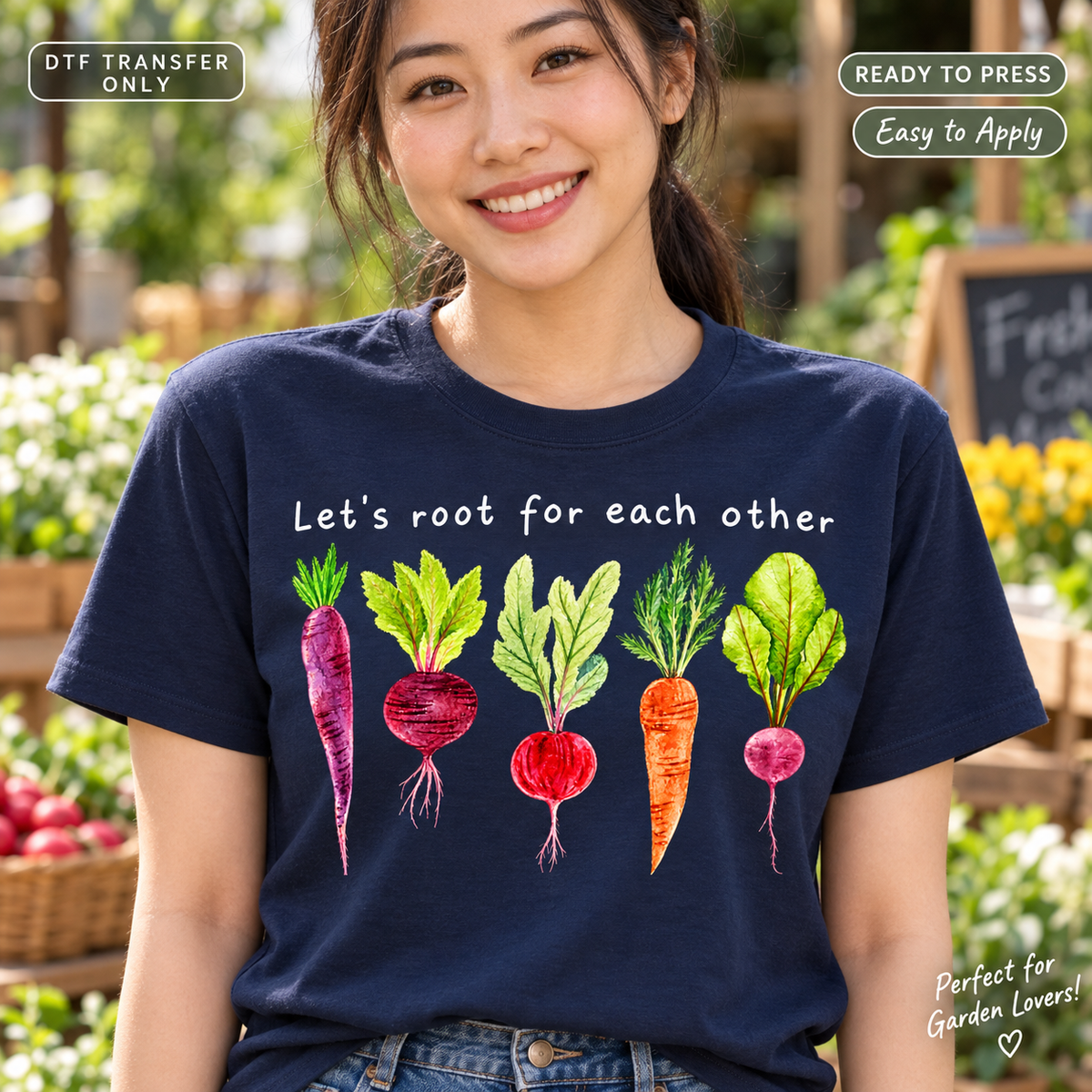 Lifestyle mockup of a woman wearing a navy shirt showing Let's Root for Each Other lettering above colorful root vegetables. DTF transfer only; shirt not included.