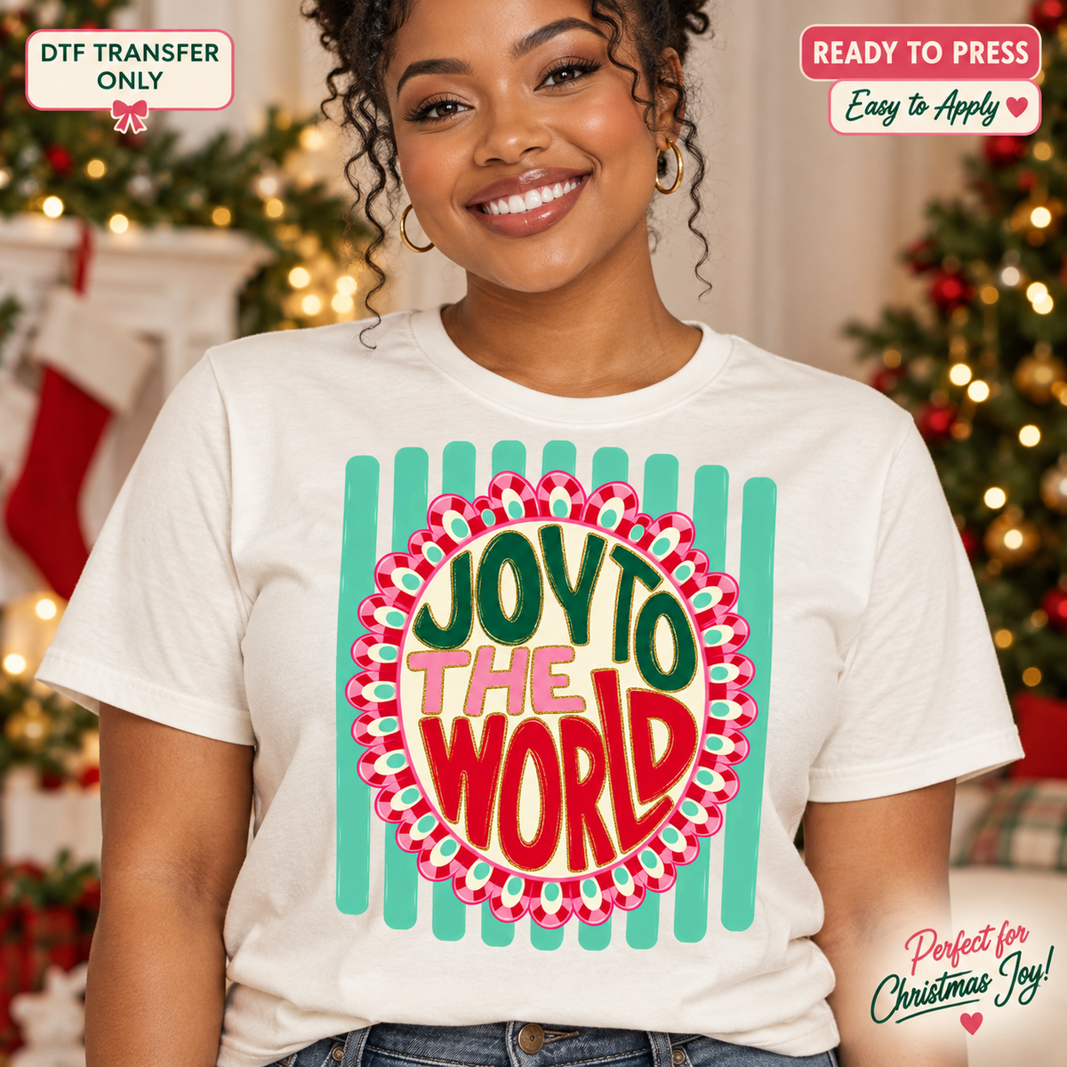 Lifestyle mockup of a woman wearing a cream shirt showing Joy to the World lettering in a decorative oval over teal stripes. DTF transfer only; shirt not included.