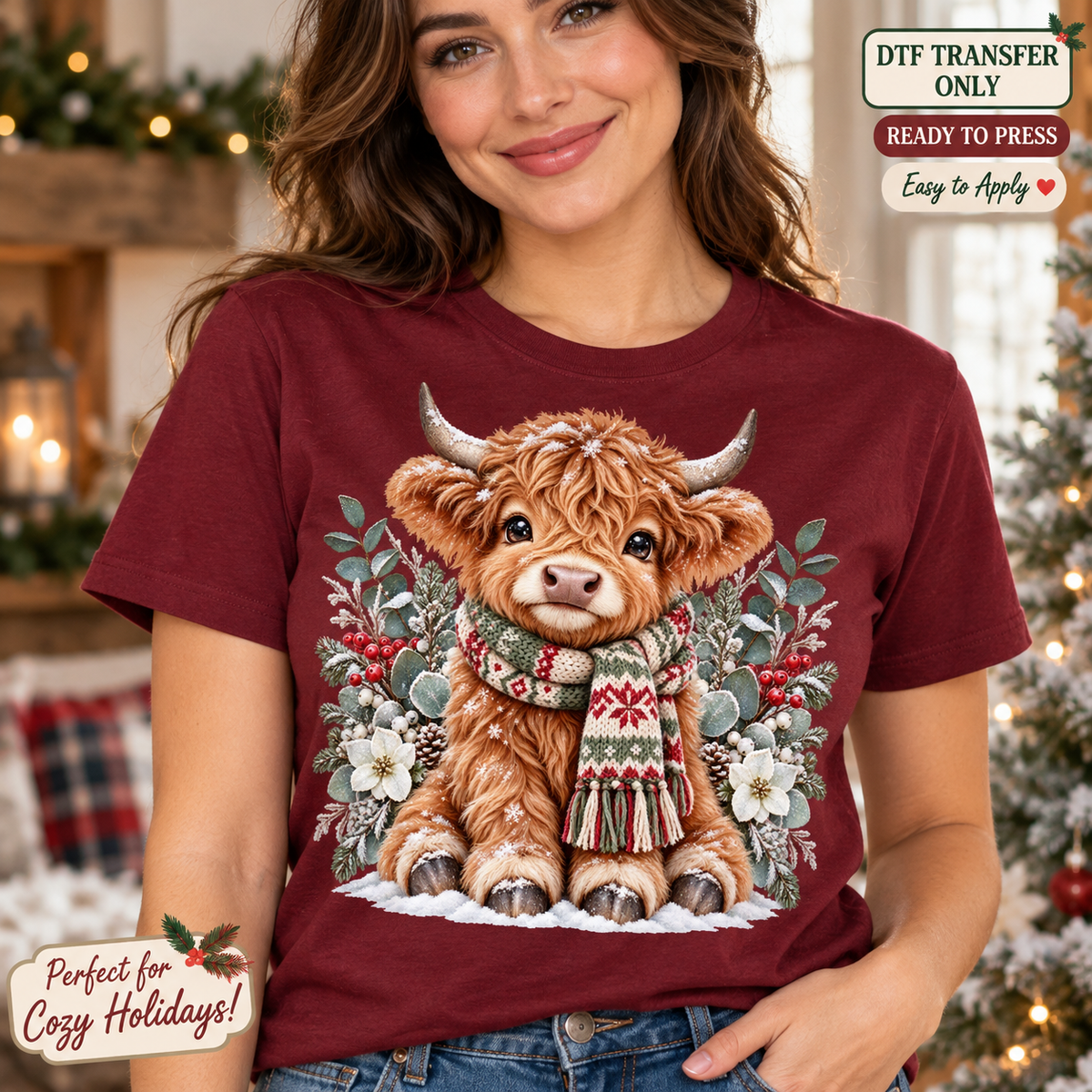 Lifestyle mockup of a woman wearing a maroon shirt showing Seated Highland cow in a red and green scarf with snowy flowers and winter greenery. DTF transfer only; shirt not included.