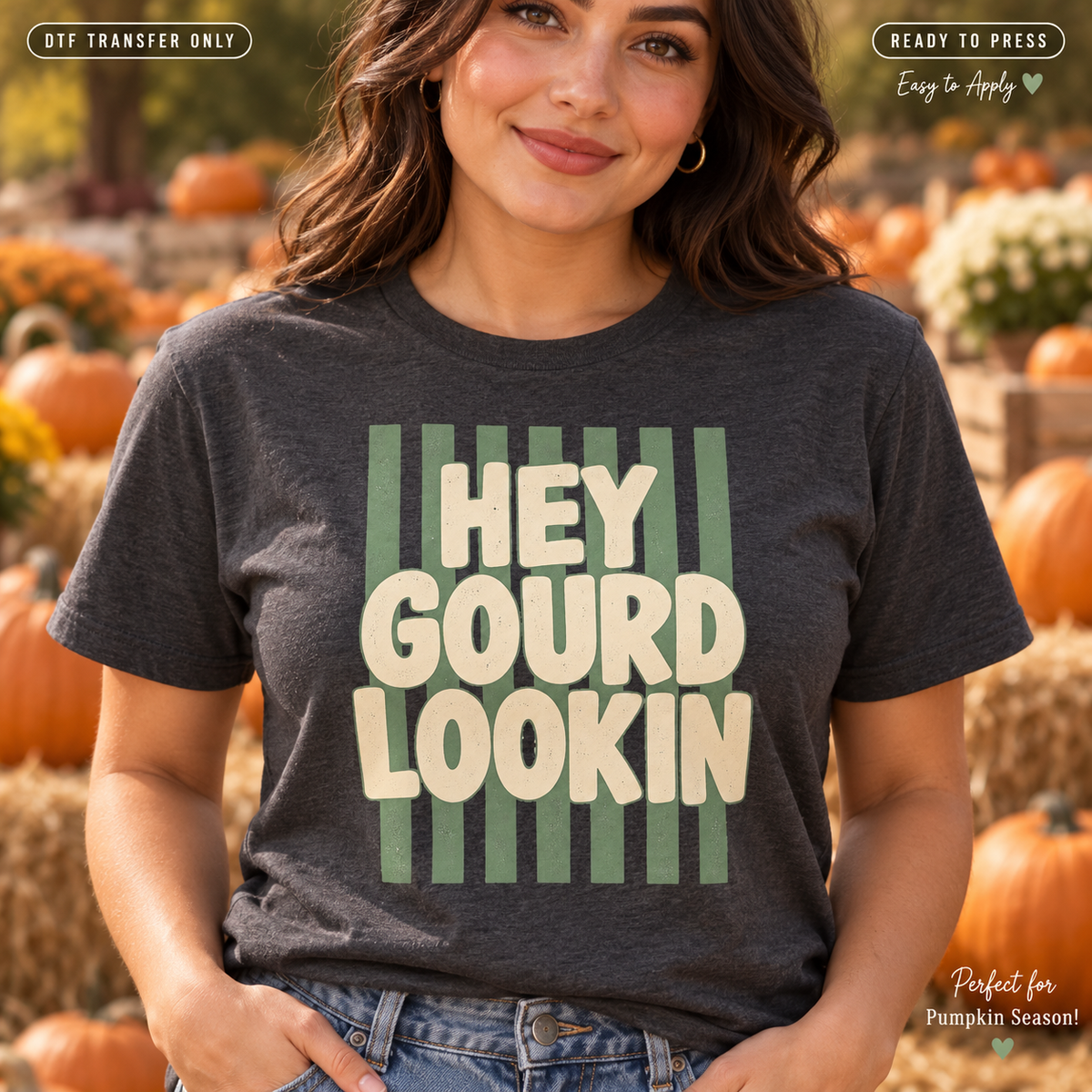 Lifestyle mockup of a woman wearing a charcoal shirt showing Hey Gourd Lookin cream lettering over green vertical stripes. DTF transfer only; shirt not included.