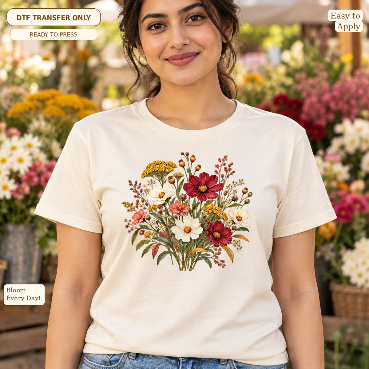 Woman wearing a cream tee with a mixed wildflower bouquet in red, white and golden tones with green foliage.