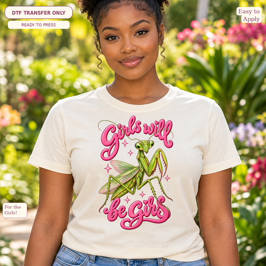 Woman wearing a cream tee with pink Girls Will Be Girls script, a green praying mantis and small stars.