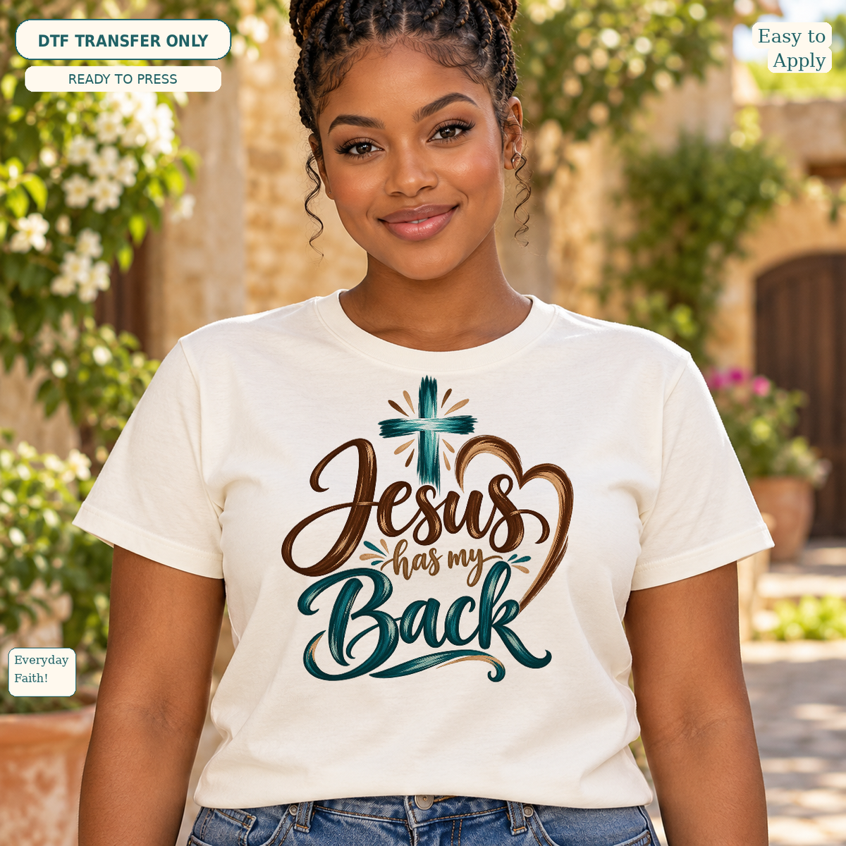 Woman wearing a cream tee with brown and teal Jesus Has My Back script and a teal cross.