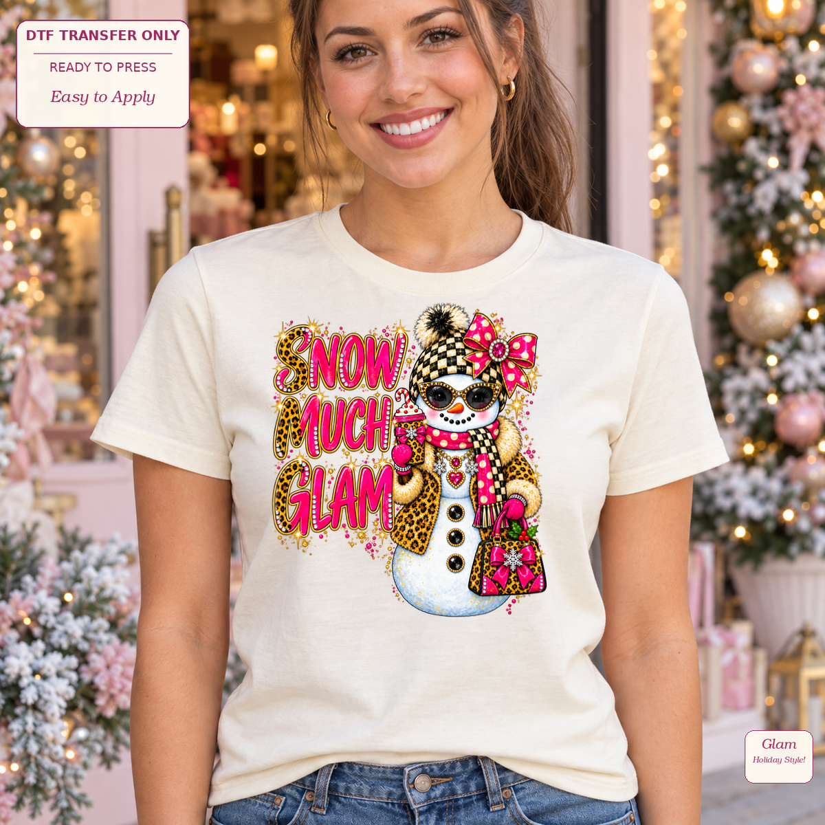 Woman in a cream tee with Snow Much Glam lettering and a snowman wearing sunglasses, leopard accents and pink accessories.