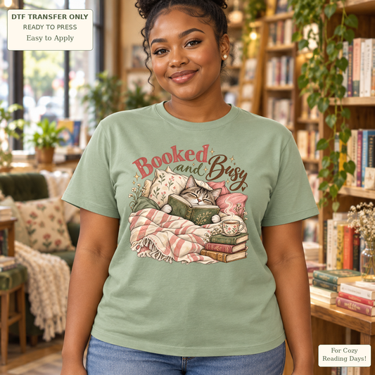 Woman in a sage green tee with Booked and Busy text and a cozy cat with a book, mug and pink checked blanket.