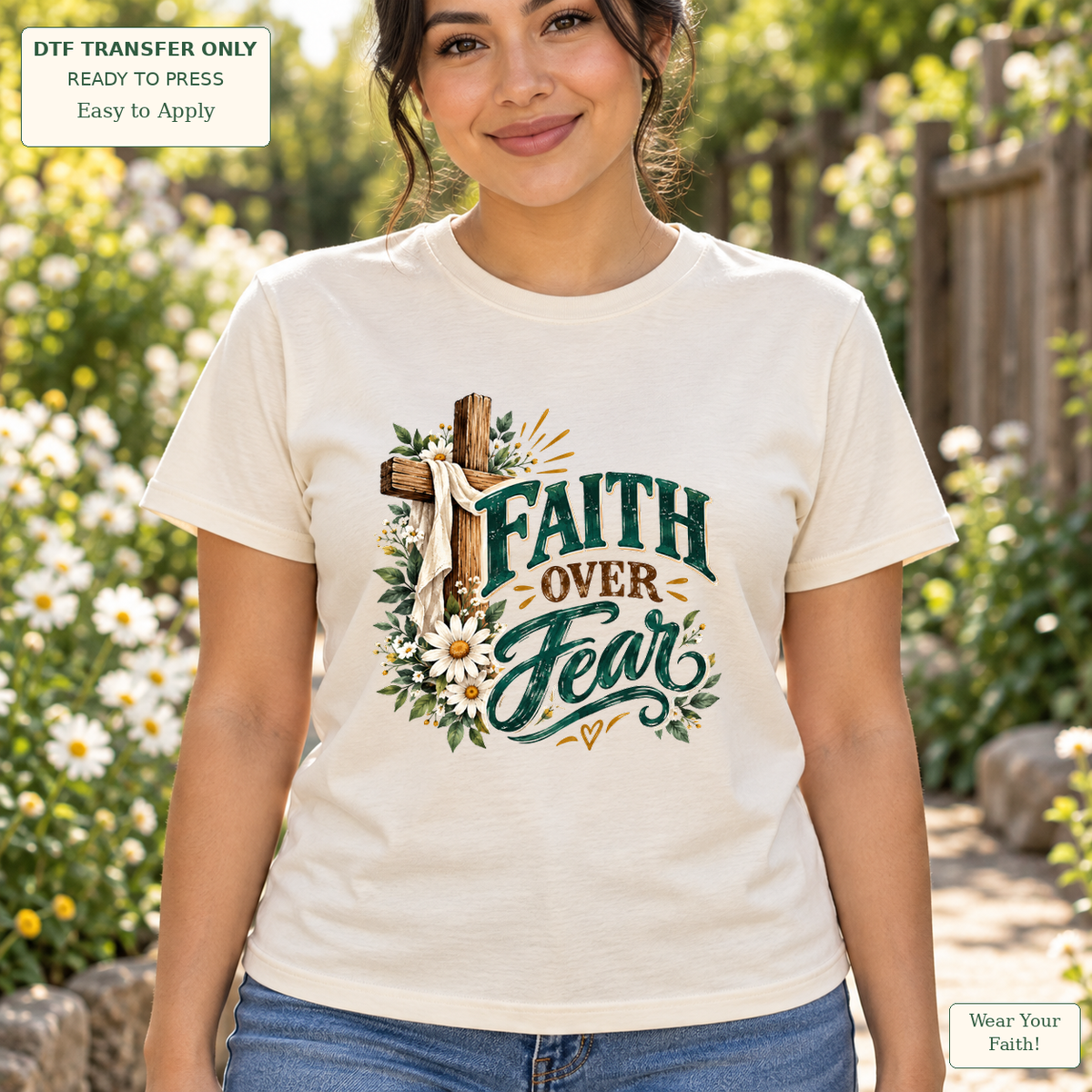 Woman wearing a cream tee with green Faith Over Fear lettering beside a wooden cross, white drape and flowers.