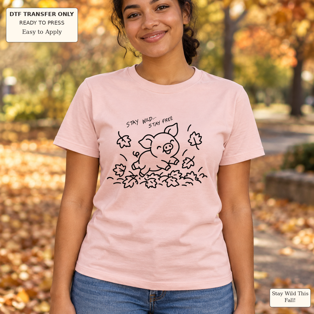 Woman wearing a pink tee with black line art of a pig jumping through leaves and Stay Wild Stay Free text.