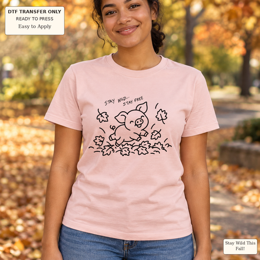 Woman wearing a pink tee with black line art of a pig jumping through leaves and Stay Wild Stay Free text.