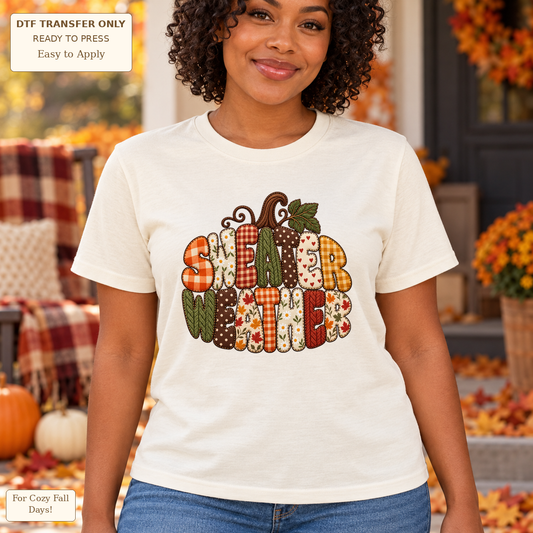 Woman in a cream tee with SWEATER WEATHER patchwork-style lettering arranged in a pumpkin shape with a stem and leaf.