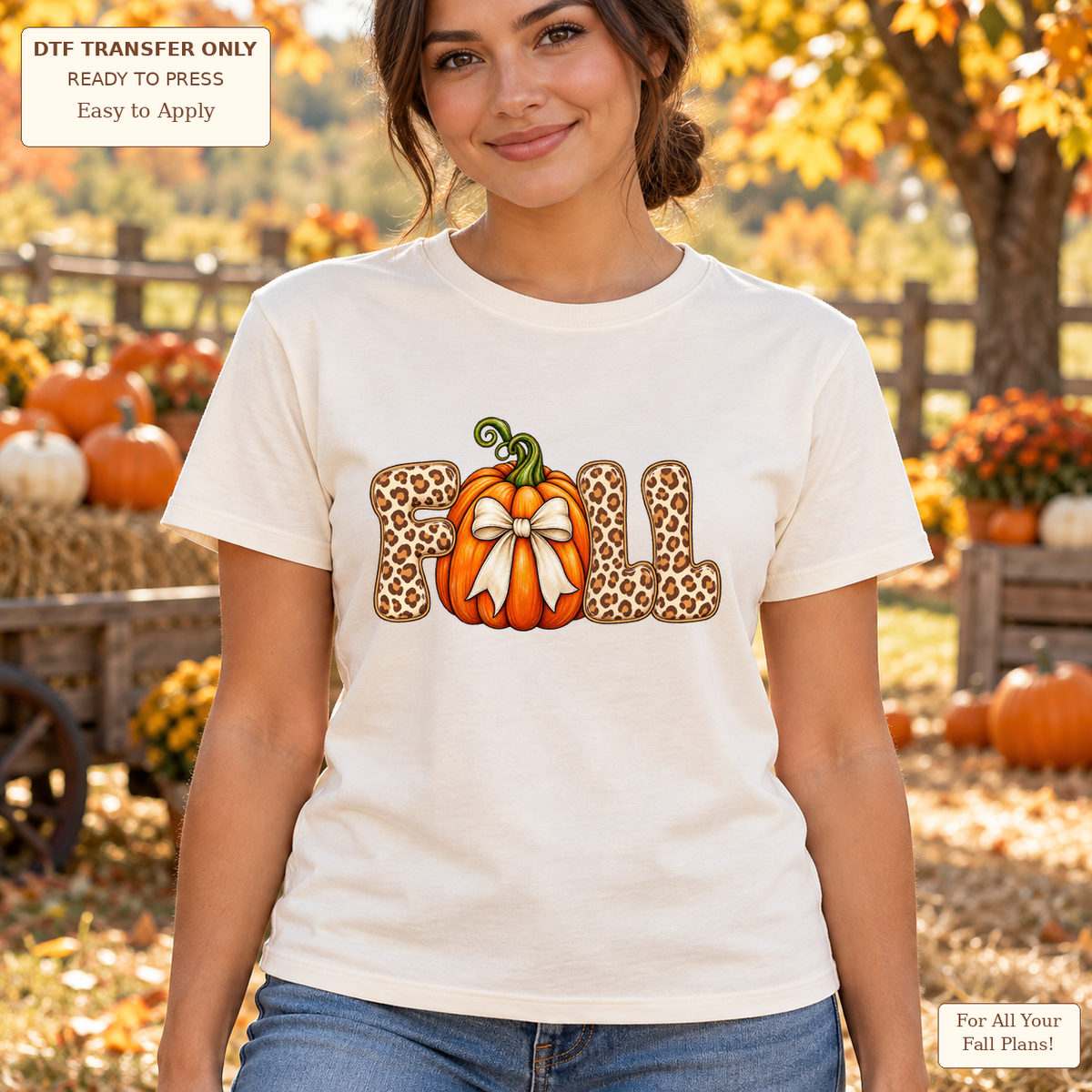 Woman wearing a cream tee with leopard-pattern FALL lettering and an orange pumpkin tied with a cream bow.