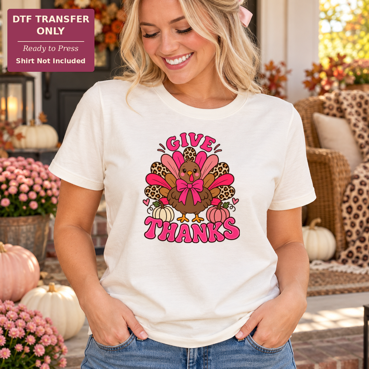 Woman wearing a cream tee with pink Give Thanks lettering and a turkey with a pink bow and pink and leopard-pattern feathers.