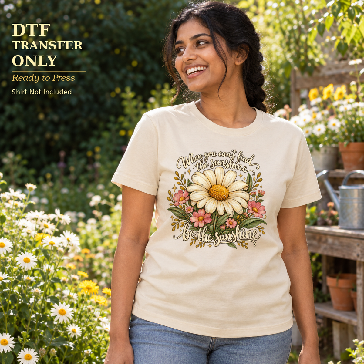 Woman wearing a cream shirt with daisies and When You Can't Find the Sunshine Be the Sunshine lettering in a garden.