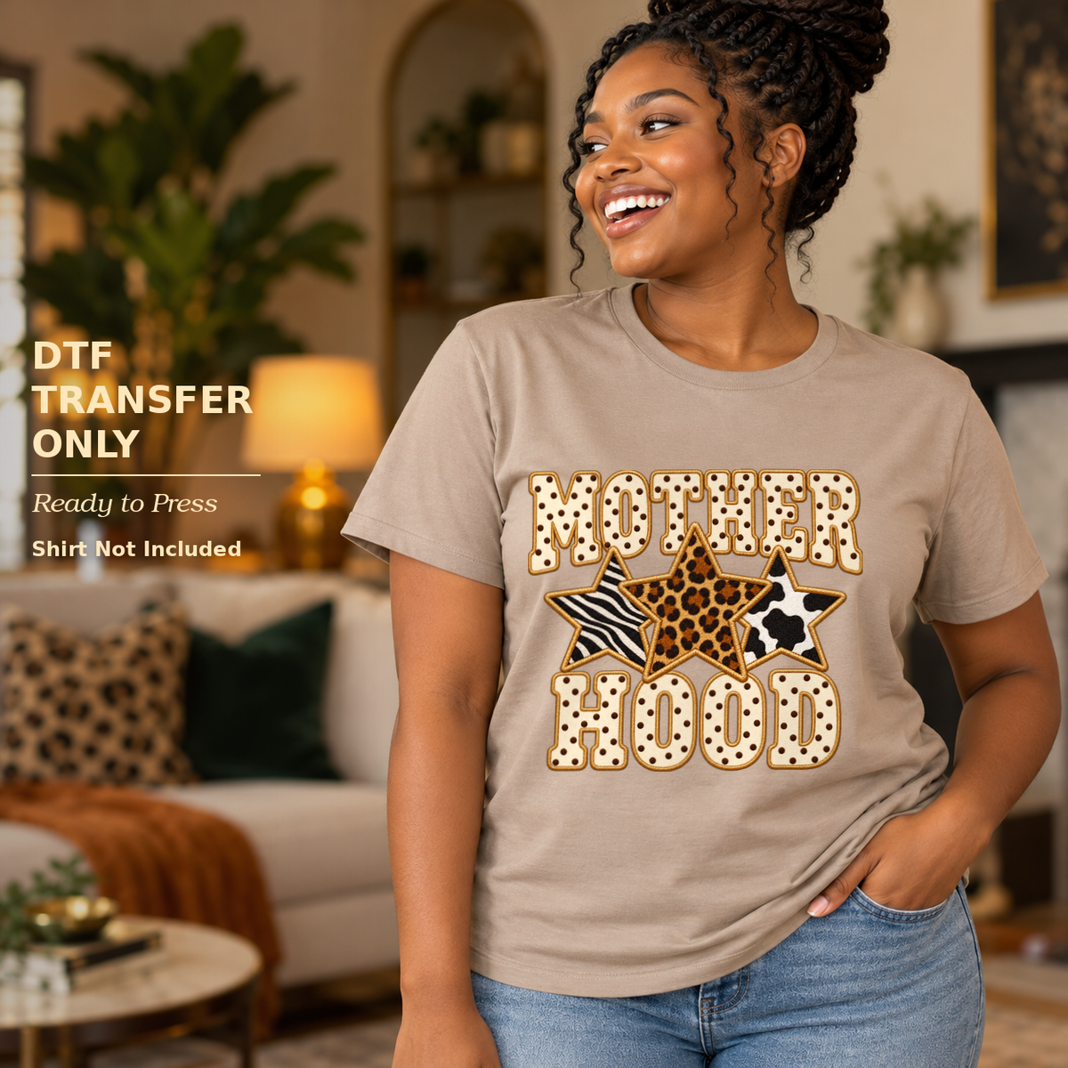 Woman wearing a tan shirt with Motherhood lettering and leopard and striped stars in a living room.