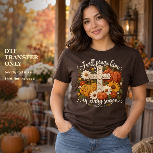 Woman in a brown shirt with I Will Praise Him in Every Season wording, a floral cross, and pumpkins on a fall porch.