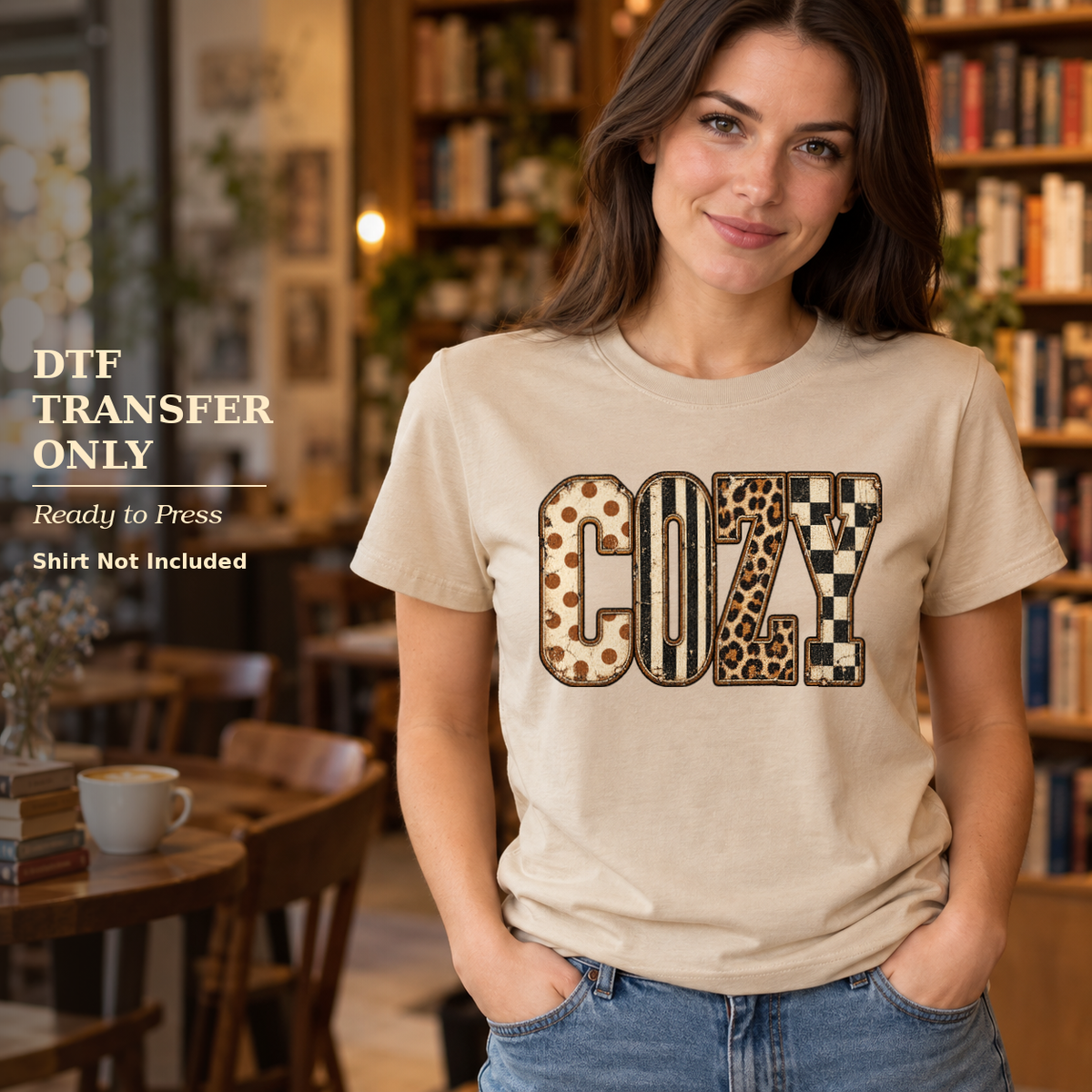 Woman wearing a cream shirt with Cozy lettering in leopard, stripe, and checkerboard patterns in a cafe.
