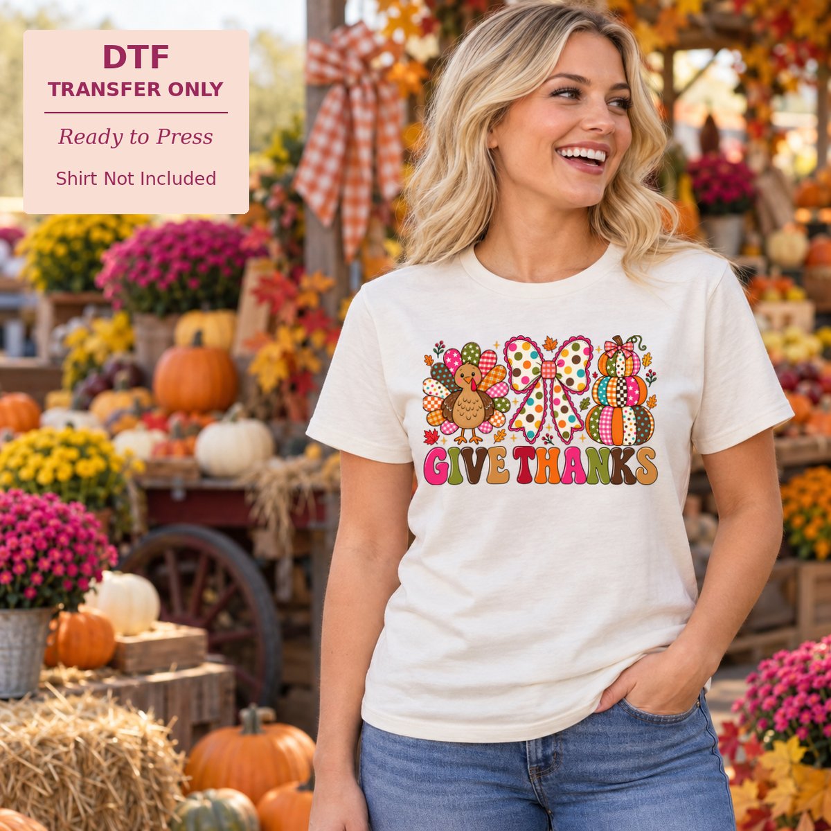 Woman wearing a white Give Thanks shirt with colorful patchwork motifs, a turkey, and pumpkins at a fall market.