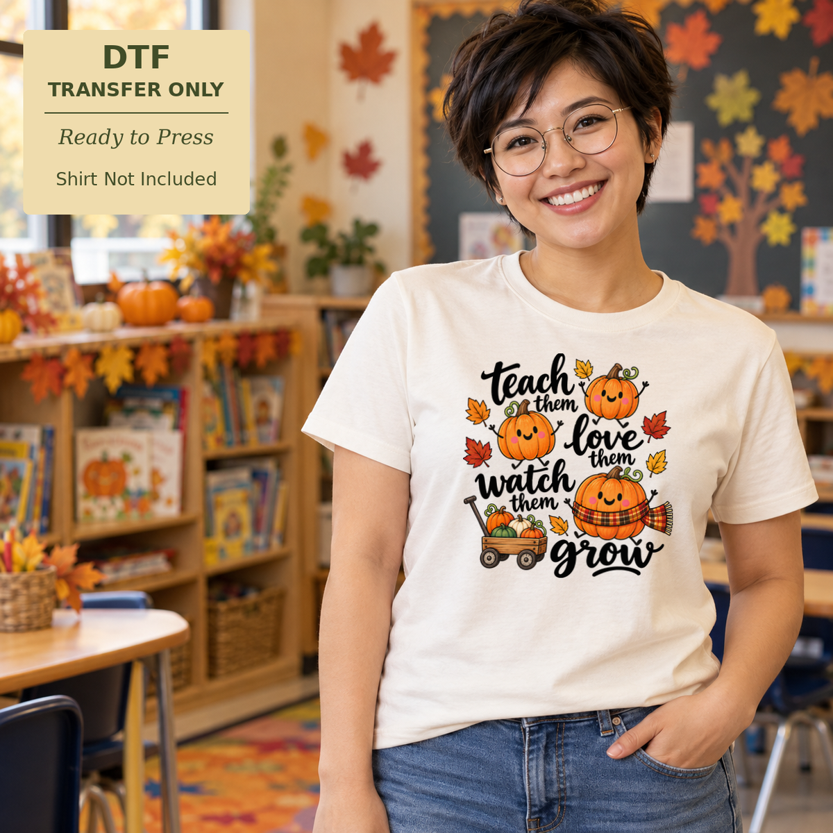 Woman in a white shirt with dark Teach Them Love Them Watch Them Grow lettering, pumpkins, and a small tractor in a classroom.