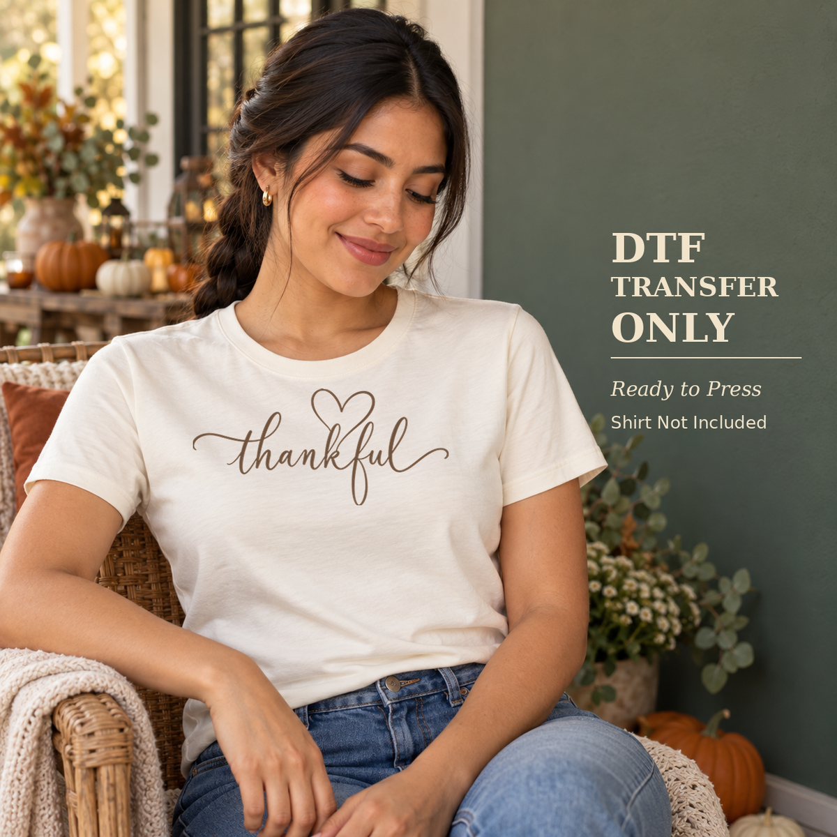 Woman wearing a cream shirt with delicate Thankful script and a simple outlined heart in a softly lit living room.