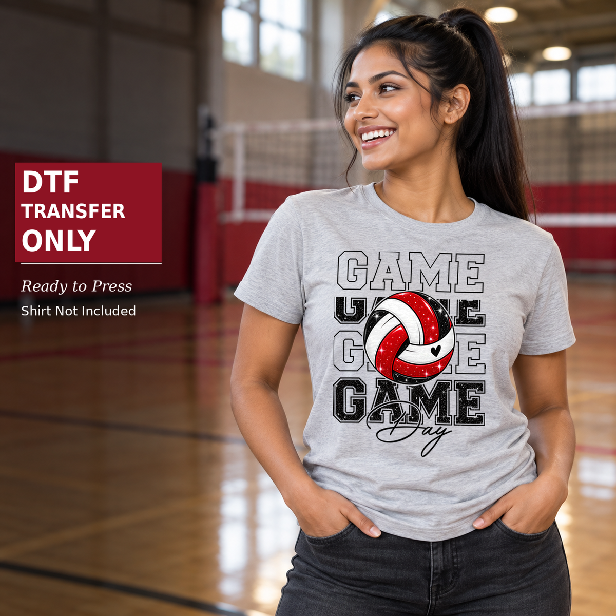Woman wearing a grey shirt with repeated Game lettering and a red, black, and white volleyball in a gym.